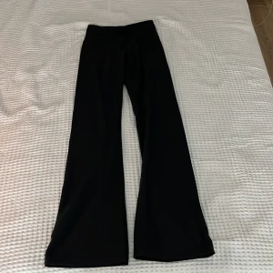 Svarta bootcut träningsbyxor Bounce XS - Svarta träningsbyxor från Bounce i storlek XS. Byxorna har bootcut-modell med utsvängda ben och hög midja. Tillverkade i ett stretchigt och mjukt syntetmaterial som passar perfekt för träning. Snygga sömdetaljer och diskret logga framtill.