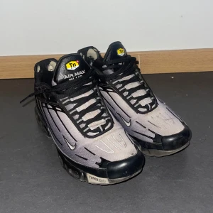 Nike Air Max Plus Tn i svart och grå - Nike Air Max Plus Tn sneakers i svart och grå med ikoniska Tn-detaljer och Tuned Air-sula. Ovandel i mesh och syntet, svarta snören och coola linjer längs sidorna. Perfekta för dig som gillar streetstyle och vill sticka ut med klassisk Nike-design.