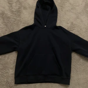 Mörkblå hoodie från Gina Tricot - Mörkblå hoodie från Gina Tricot i storlek S. Klassisk modell med huva och stor magficka framtill. Tröjan har långärmade ärmar och är gjord i mjukt material som passar perfekt för chill dagar. Enkel och stilren design utan mönster eller detaljer. Den har en rosa fläck på ärmen, men den är ganska liten så jag kan inte hitta den nu när jag lägger upp annonsen, men jag vet att den finns där. Den har också en fläck på framsidan som bara syns i ett visst ljus. Den är knappt synlig.