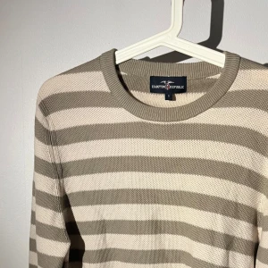 Randig beige och olivgrön stickad tröja - Snygg stickad tröja från Hampton Republic i storlek S. Tröjan har breda horisontella ränder i beige och olivgrön, rund halsringning och långa ärmar. Perfekt för dig som gillar klassisk och chill stil med lite preppy vibe.