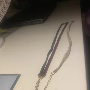 Set med tre sammetshalsband - Tre snygga choker-halsband i sammet med guldfärgade kedjor och lås. Färgerna är svart, vinröd och champagnebeige. Perfekt för att ge din outfit en cool och trendig vibe. Justerbar längd med kedja baktill.