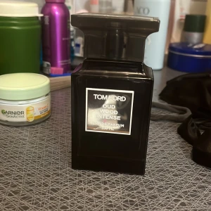 Tom Ford Oud Wood Intense 100ml - Tom Ford Oud Wood Intense Eau de Parfum i en lyxig, svart och fyrkantig glasflaska på 100 ml. Flaskan har en elegant och modern design med tydlig etikett framtill och texten 'TESTER' på baksidan. Perfekt för dig som gillar exklusiva och djupa dofter. (finns ganska lite kvar som du kan se i sista bilden )