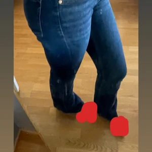 Blå bootcut jeans med låg midja - Säljer ett par klassiska blå jeans med bootcut-modell och lågmidja. Jeansen har en snygg mörkblå tvätt, raka bakfickor och är tillverkade i mjukt denimtyg. Perfekta för dig som gillar en tidlös och avslappnad look.