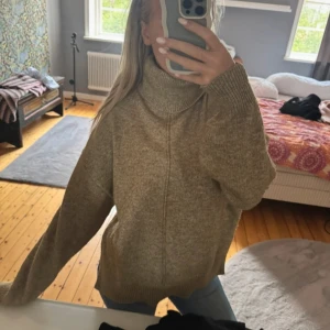 Beige polotröja i stickad ull - Säljer en oversized beige polotröja i mjuk stickad ull. Tröjan har hög krage och långa ärmar med breda muddar. Perfekt för dig som gillar chill och comfy vibes under kalla dagar. Passar till jeans eller leggings för en avslappnad look.