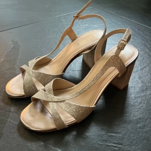 Klackskor glittriga TIAMO - Säljer ett par snygga sandaler från Tiamo i glittrigt guld, de är använda 1 gång och användes för bal💕