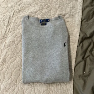 Ralph lauren tröja  - Snygg grå tröja från Polo Ralph Lauren i slim fit med rund hals och diskret broderad logga på bröstet. Tillverkad i mjuk pima bomull som känns skön mot huden. Perfekt för dig som gillar stilrena och klassiska plagg med en modern passform. Väldigt fin och bra kvalitet, ny pris på denna är 2500! 