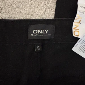 Svarta high waist jeans från ONLY - Svarta jeans från ONLY, modell Emily Straight med hög midja och croppad längd vid ankeln. Klassisk femficksdesign och raka ben. Tillverkade i bomullsmix för en bekväm känsla. Perfekta för dig som gillar en clean och stilren look.