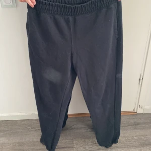 Svarta mjukisbyxor med resår - Svarta mjukisbyxor med elastisk midja och muddar vid bensluten. Byxorna har en bakficka och är gjorda i mjukt bomullsmaterial, perfekta för chill dagar eller när du vill vara extra bekväm.