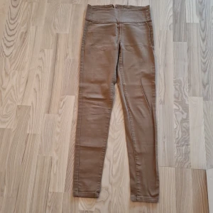 Beige skinny leggings från Pieces - Snygga beige leggings från Pieces med hög midja och skinny passform. De har två bakfickor och en cool dragkedja bak. Materialet är mjukt och stretchigt, perfekt för en chill och stilren look. Passar dig som gillar enkla och bekväma byxor med lite edge.