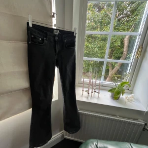 Svarta bootcut jeans från 157 - Svarta jeans från 157 med klassisk femficksdesign och bootcut-ben. Jeansen har lågmidjad passform och är tillverkade i ett mjukt denimtyg som sitter skönt. Perfekta för dig som gillar en tidlös look med lite utsvängda ben.