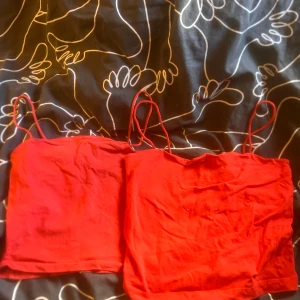 Röda linne-toppar från Gina Tricot - Två röda linne-toppar från Gina Tricot med tunna axelband. Enkla och stilrena, perfekta att matcha med jeans eller kjol. Finns i storlek XS och M. Säljes tillsammans eller separat, hör av dig om du vill ha båda eller bara en!