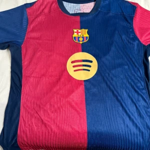 FC Barcelona matchtröja röd/blå - Säljer en FC Barcelona tröja.  Rund hals, korta ärmar och tillverkad i lätt, ventilerande material. Har aldrig använt. Pris kan diskuteras men slutpris är 110, köpte den för 400. 