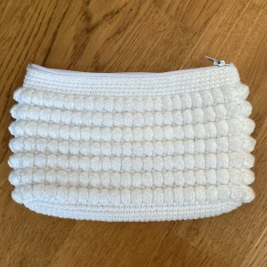 Vit virkad necessär med dragkedja - Superfin hemmagjord  vit necessär i virkat material med bubblig struktur. Necessären har ett ljusgrönt innerfoder och stängs med en vit dragkedja upptill. Perfekt storlek för smink eller småprylar. Höjd 12cm, bredd 20cm, Du står för frakten, vid mer info skriv