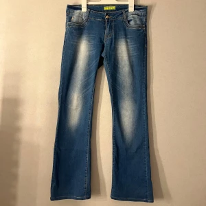 Blå bootcut jeans från Miss Curry - Snygga blå bootcut jeans från Miss Curry med  ljusa partier framtill och baktill. Jeansen har dekorativa nitar på bakfickorna och guldig knapp framtill. Klassisk femficksmodell i stretchig denim med kontrastsömmar. Har lagt in ett snöre inne i byxorna då den va lite för stora för mig i midjan men verkligen inget som syns när den sitter på, går att ta ut den om man inte vill ha den kvar. E verkligen jätte jätte Lågmidjade vid frågor elr mer bilder e de bara att kontakta mig🤗