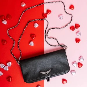  Zadig & Voltaire rock grained leather - Säljer en svart axelväska i skinn från Zadig & Voltaire med silverfärgad kedjerem och ikonisk vingedetalj framtill. Väskan har dragkedja både fram och bak, och en stilren, rektangulär form som passar till många looks. Nypris 3500kr.