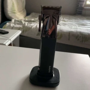BaByliss hårtrimmer svart/krom - Snygg hårtrimmer från BaByliss i svart och krom med laddningsstation. Ergonomiskt handtag och justerbar längd. Perfekt för att fixa frisyren hemma med stilren design och digital display på sidan.