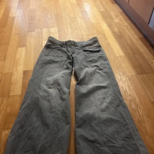 Gråa wide byxor i bomull - Säljer ett par gråa byxor med breda ben och raka sömmar. Byxorna har klassiska bakfickor och bälteshällor, tillverkade i mjuk bomull. Perfekta för dig som gillar en avslappnad och trendig stil. Används inte då dom är lite stora, aldrig använd. Storlek 40 så lite stor i midjan 