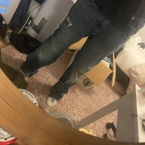 True Religion Rocco relaxed skinny jeans - Säljer ett par blå True Religion Rocco relaxed skinny jeans i storlek 34. Jeansen har klassiska kontrastsömmar, slitningar och en snygg bakficka med broderad logga. Modellen är relaxed skinny och materialet är klassisk denim. Perfekta för dig som gillar streetwear. Utsydda till bootcut/flare. 