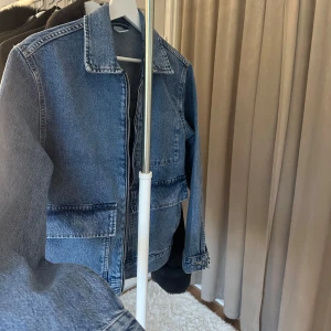  jeansjacka - Snygg blå jeansjacka med raka linjer och dragkedja framtill. Jackan har stora fickor och klassisk krage. Den är ENBART testad och hann inte skicka tillbaka den. Den är slutsåld på hemsidan.💕