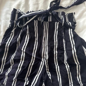 Svartvita randiga shorts med knytband - Snygga svartvita shorts från Bershka med vertikala ränder och högt midjeband med knyt. Luftigt material i viskos som passar perfekt till varma dagar. Shortsen har en relaxed fit och ger en chill vibe till din outfit.