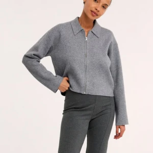 Grå croppad overshirt med dragkedja - Säljer en stilren grå croppad overshirt, med klassisk krage och hel dragkedja framtill. Jackan har raka, långa ärmar och är tillverkad i mjukt material som ger en clean och modern look. INTRESSEKOLL! 