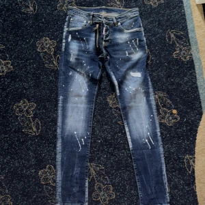 Dsquared2 Jeans - Snygga blå skinny jeans från Dsquared2 med coola färgstänk och slitningar. Jeansen har klassisk femficksdesign, låg midja och detaljerad patch på insidan. Perfekta för dig som vill sticka ut med en edgy streetstil.