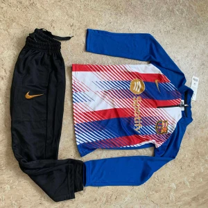 FC Barcelona långärmad fotbollströja Nike - Säljer en FC Barcelona långärmad fotbollströja från Nike med färgglada ränder i blått, rött och vitt. Tröjan har klubbmärke och Spotify-logga på bröstet samt dragkedja vid halsen. Materialet är lätt och andas, perfekt för träning eller match.
