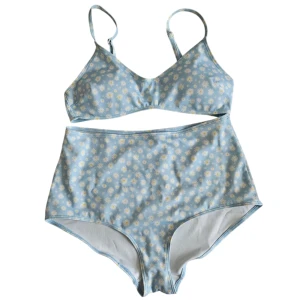 Blå bikini med prästkragar, high waist - [ALDRIG ANVÄND] Supersöt ljusblå bikini med vita och gula prästkragar. Överdelen har smala axelband och spänne i ryggen, medan underdelen är high waist för en retrovibe. Tillverkad i stretchigt material med 84% polyester och 16% elastan. Perfekt för strandhäng i sommar! 