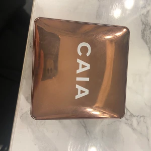 CAIA Glow Bronzer Monaco - Säljer en CAIA Glow Bronzer i nyansen Monaco. Kommer i en snygg, bronsfärgad fyrkantig dosa med spegel. Pudret har en varm, gyllenbrun ton och en lätt skimrig finish som ger glow till ansiktet. Vegansk och tillverkad i Italien.