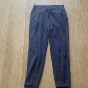 Mörkblå mjukisbyxor Peak Performance - Mörkblå mjukisbyxor från Peak Performance med snörning i midjan, ribbade muddar vid benslut och fickor både fram och bak. Sköna och stilrena, perfekta för chill eller träning. Tillverkade i mjuk bomullsmix för extra komfort.