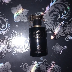 Svart lyxig parfymflaska med gulddetaljer helt tom - Säljer en elegant parfym i svart glasflaska med exklusiva gulddetaljer och dekorativ kork. Flaskan rymmer 100 ml och har en lyxig känsla med fina ornament på framsidan. Perfekt för dig som gillar stilrena och sofistikerade dofter. Helt tom