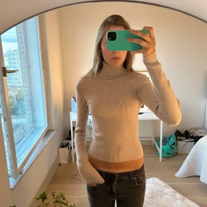 Beige ribbad polotröja från mango  - Säljer denna super snygga beiga ribbade polotröjan med lång ärm och tight passform från mango. Använd endast en gång.