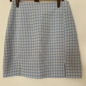 Blåvit rutig kortkjol med slits - Supersöt blå och vit rutig kortkjol med två små slitsar framtill. Storlek xs men är insydd så passar även xxs🩵🤍