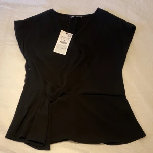 Svart omlottopp med knyt från Zara - Säljer denna jättefina topp ifrån Zara, säljer för att den inte kommit till användning & den är lite för liten💞Toppen är i st M men skulle säga att den sitter som en S💞