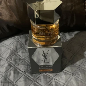 YSL L'Homme L'Intense EdP 60ml - YSL L'Homme L'Intense Eau de Parfum i 60ml flaska. Parfymen kommer i en stilren glasflaska med sexkantigt silverlock och bärnstensfärgad vätska. Förpackningen är svart med silverdetaljer och tydlig YSL-logga. En maskulin och elegant doft.