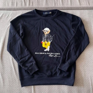 Mörkblå Polo Bear tröja - Säljer en helt oanvänd Polo Bear by Ralph Lauren tröja färgad mörkblå. Tröjan är i storlek M och är i extremt bra skick eftersom den är helt oanvänd. Originalpriset på denna ligger på 3000kr