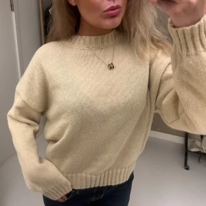 Beige stickad tröja med ribbade detaljer - Supermjuk beige stickad tröja med rund hals och ribbade muddar vid ärmslut och nederkant. Tröjan har en relaxed passform och är perfekt att slänga på sig när det är kyligt ute. Enkel och stilren design som funkar till allt. Aldrig använd!❤️