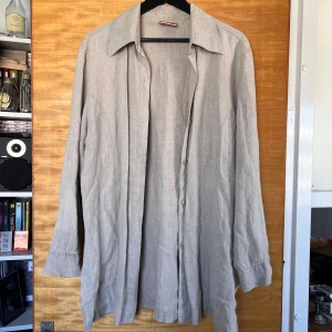 Beige linneskjorta - Oversized beige linneskjorta, mycket flowig och härlig, perfekt såhär till sommaren. Skjortan har klassisk krage, knappar framtill och långa ärmar med knapp vid manschetten.