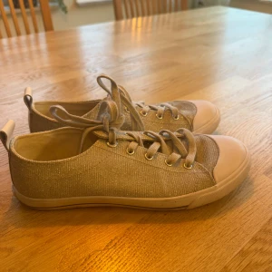 Glittriga sneakers - Säljer dessa snygga sneakers då de inte längre passar mig. De är grå med glittrig finish och klassisk snörning. Skorna har rund tå, platt sula och detaljer i textil. Fortfarande i väldigt bra skick, inga skador eller fläckar. 