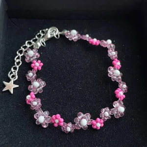 Handgjort- Sött pärlarmband med blommor - Supergulligt armband med små blommor av rosa och vita pärlor. Armbandet har en silverfärgad kedja med stjärnberlock och justerbart lås. Perfekt accessoar för dig som vill ha en lekfull och färgglad detalj till din stil.