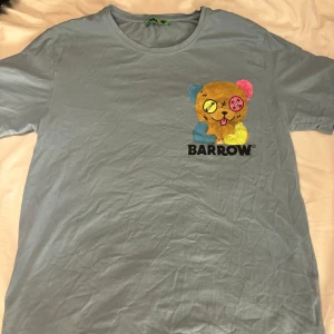 Blå t-shirt från Barrow med nalletryck - Snygg blå t-shirt från Barrow med ett stort färgglatt nalletryck både fram och bak. T-shirten har rund halsringning och korta ärmar. Trycket har coola detaljer i gult, rosa och blått samt texten 'I JUST WANT TO FEEL GOOD' på ryggen. Perfekt för dig som gillar streetwear med edge. Storlek medium