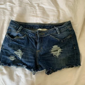Mörkblå slitna jeansshorts - Ett par snygga mörkblå jeans shorts med mycket slitasch på ben sluten