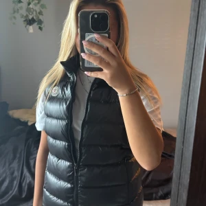 Svart Moncler väst - Bra skick men använd. Säljer för att den inte kommer till användning längre. Den är liten i storleken, passar tjejer som har storleken xs/s och upp till ca 165cm lång. 