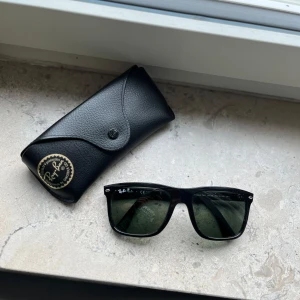 Svarta Ray-Ban Wayfarer solglasögon - Helt nya svarta Ray-Ban Boyfirend solglasögon med polariserat glas och ikonisk logga på skalmen. Snygg, tidlös design med robust plastbåge. Kommer med original Ray-Ban-fodral. Perfekta för att lyfta din stil i solen.