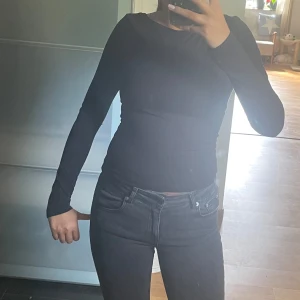 Svart långärmad topp med öppen rygg - Säljer en svart långärmad topp med tight passform och öppen rygg. Enkel och stilren design som passar perfekt till jeans eller kjol. Tunn och stretchig, vilket gör den riktigt skön att bära. Perfekt för dig som gillar minimalistisk stil.