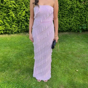 Ohpolly festklänning  - .Säljer min Ohpolly klänning i ljusrosa med volanger och stenar. I storlek 12 men insydd till  s/m 