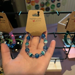 Blått pärlarmband med ränder - Unikt handgjort armband med blå och vita pärlor. Pärlorna är glittriga och vissa har coola ränder i blått och vitt. Armbandet har även transparenta pärlor som ger extra bling. Perfekt accessoar för att lyfta din stil!