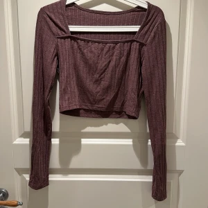 Vinröd ribbad croppad topp - Trendig vinröd croppad topp med ribbad struktur och långa ärmar. Snygg fyrkantig urringning som ger en cool vibe. Perfekt att matcha med höga jeans eller kjol för en stilren look.