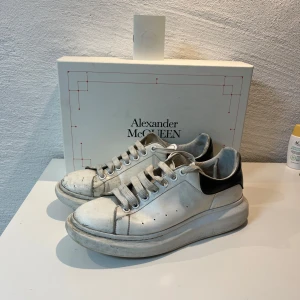 Alexander McQueen vita sneakers - Vita Alexander McQueen i storlek 43. Box och certifikat ingår, samt extra skosnöres! Liten flaw då de är ett litet hål i sulan, annars i gott skick trots väl använda och smutsiga. Skorna är i läder och har en lång livslängd!