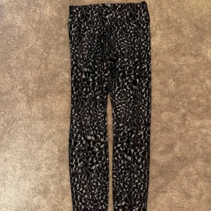 Leopardmönstrade svarta leggings - Snygga mörkblåa leggings med leopardmönster i gråa och svarta toner. De har en tight passform och hög midja, perfekta för att sticka ut lite extra. Materialet är mjukt och stretchigt, vilket gör dem riktigt bekväma att bära hela dagen.